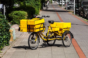Gelbes dreirädriges Elektrolastenfahrrad mit gelben Paketen beladen
