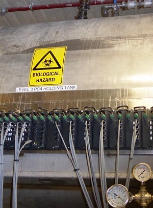 großer Tank mit vielen Schlauchanschlüssen und Warnschild
