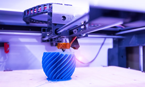 Example of an additive manufacturing process: a 3D printer produces a round blue object.