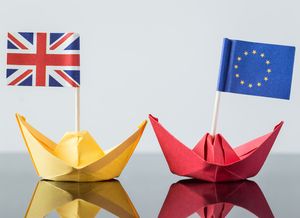 Flags of EU blue with 12 yellow stars and Great Britain 2 red crosses one behind the other, white outlined on blue background