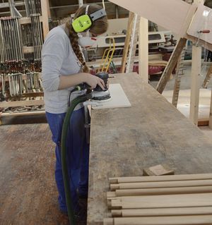 Femme avec protection auditive et respiratoire lors du mesurage de poussière à une machine pour le travail du bois