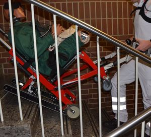 Transport d'un patient dans un escalier à l'aide d'une chaise portoir à chenilles