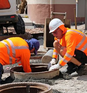 Bauarbeiter die im Freien arbeiten und Schutzkleidung sowie Kopfbedeckung tragen