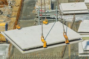 Große Betonplatte hängt an vier Ketten an einem Baukran