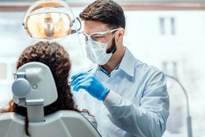 Dentist wearing a mask and face shield during patient treatment