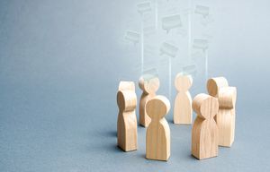 Wooden figures stand in a circle, with speech bubbles outlined above them