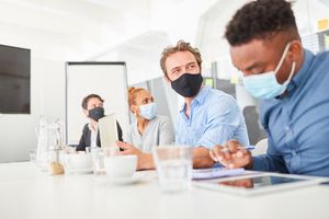 Groupe de personnes portant des masques dans une salle de réunion