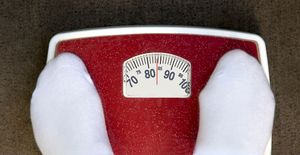 Pieds d'une personne en chaussettes blanches sur une balance pesant 84 kg