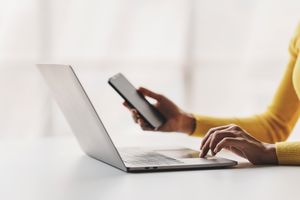 Woman working at a desk with smartphone and laptop computer 