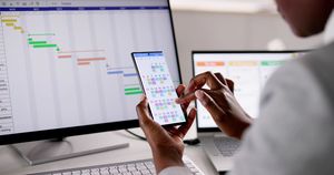 Person working at a desk with smartphone and desktop computer