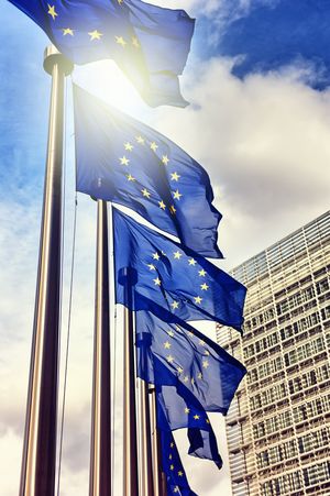 Mehrere Fahnenmasten mit EU-Flaggen vor einem großen Gebäude