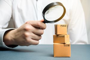 Someone looks at three boxes of goods through a magnifying glass