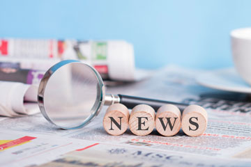 Zeitung und Lupe auf einem Tisch, das Wort "News" steht auf vier Würfeln. Klick öffnet die Seite Weniger tödliche Arbeitsunfälle in den Top 10 der vernachlässigten Nachrichten