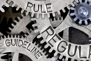 Ineinandergreifende Zahnräder, die mit Rule, Regulation, Guideline beschriftet sind.