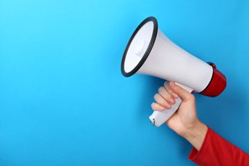 Eine Hand hält ein Megaphon.. Klick öffnet die Seite GDA-Befragung von Betrieben und Beschäftigten zeigt Fortschritte und Handlungsbedarf