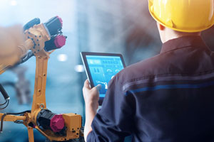 Ein Werksarbeiter steuert einen Industrieroboter über ein Tablet.