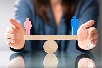 Eine Frau und ein Mann befinden sich auf einer Waage in Balance.. Klick öffnet die Seite EUROGIP veröffentlicht Studie zu geschlechtsspezifischen Aspekten im Arbeitsschutz in Europa