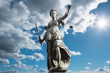 Statue einer Justitia vor blauem Himmel mit Wolken