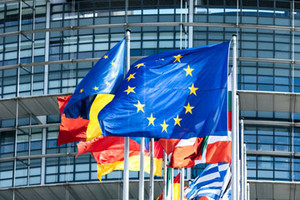 EU flag and flags of several European countries in front of a large building