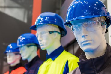 Vier Schaufensterpuppen, die blaue Schutzhelme und Schutzbrillen tragen