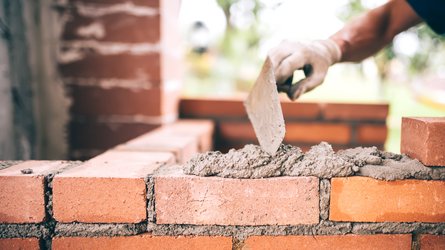 Rote Ziegelsteine werden zu einer Mauer gemauert.