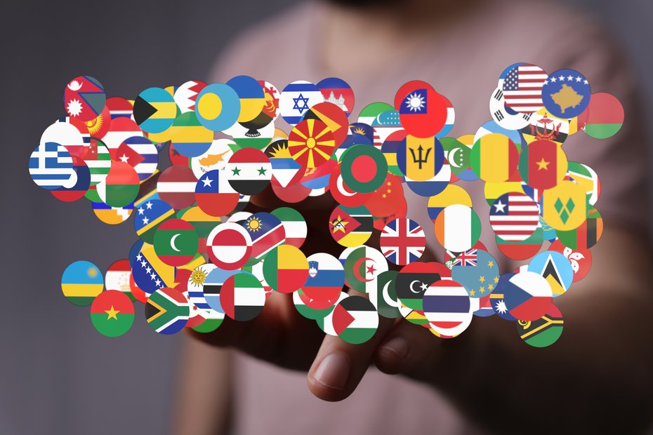 Viele verschiedene Länderflaggen der ganzen Welt in runder Form vor einer menschlichen Hand