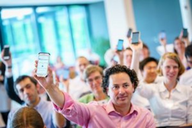 Teilnehmende der EUROSHNET-Konferenz halten ihre Smartphones hoch