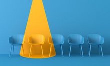 Gelber Stuhl steht in einer Reihe blauer Stühle im Spotlight 