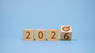 Holzwürfel bilden die Zahl 2026. Der letzte Würfel mit der 6 ist leicht gekippt, auf der angrenzenden Würfelfläche sieht man eine Zielscheibe. . Klick öffnet die Seite Europäische Kommission veröffentlicht Arbeitsprogramm 2026 für die europäische Normung
