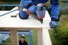 Handwerker, der mit einer Bohrmaschine ein Loch in eine Holzplatte bohrt.