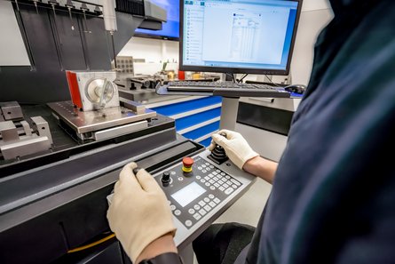 Arbeiter vor einer Maschine mit einem Bedienpanel und einem Bildschirm