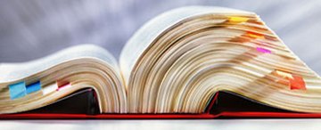 Aufgeklapptes Gesetzbuch mit bunten Seitenmarkierungen