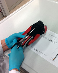 Cutting a glove through the middle to obtain a test sample