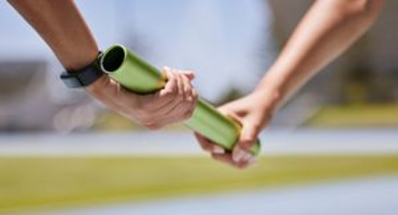 A relay baton is passed from one hand to another