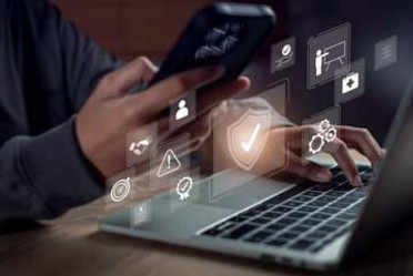 Nahaufnahme von Händen, die einen Laptop und ein Smartphone mit digitalen Schnittstellensymbolen bedienen, die für Sicherheit am Arbeitsplatz, digitale Governance, Compliance-Überwachung und Risikokontrolle in einer modernen Technologieumgebung stehen. 