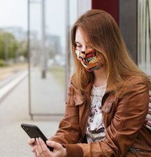 Femme avec masque barrière sur une plate-forme, regardant son téléphone portable.