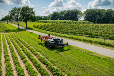 Eine fahrerlose mobile Landmaschine im Einsatz auf einem Feld, daneben befindet sich ein landwirtschaftlicher Nutzweg.