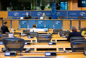 Sitzungssaal des EU-Parlaments: Blick über Tische hinweg, mit einigen besetzten Stühlen. 