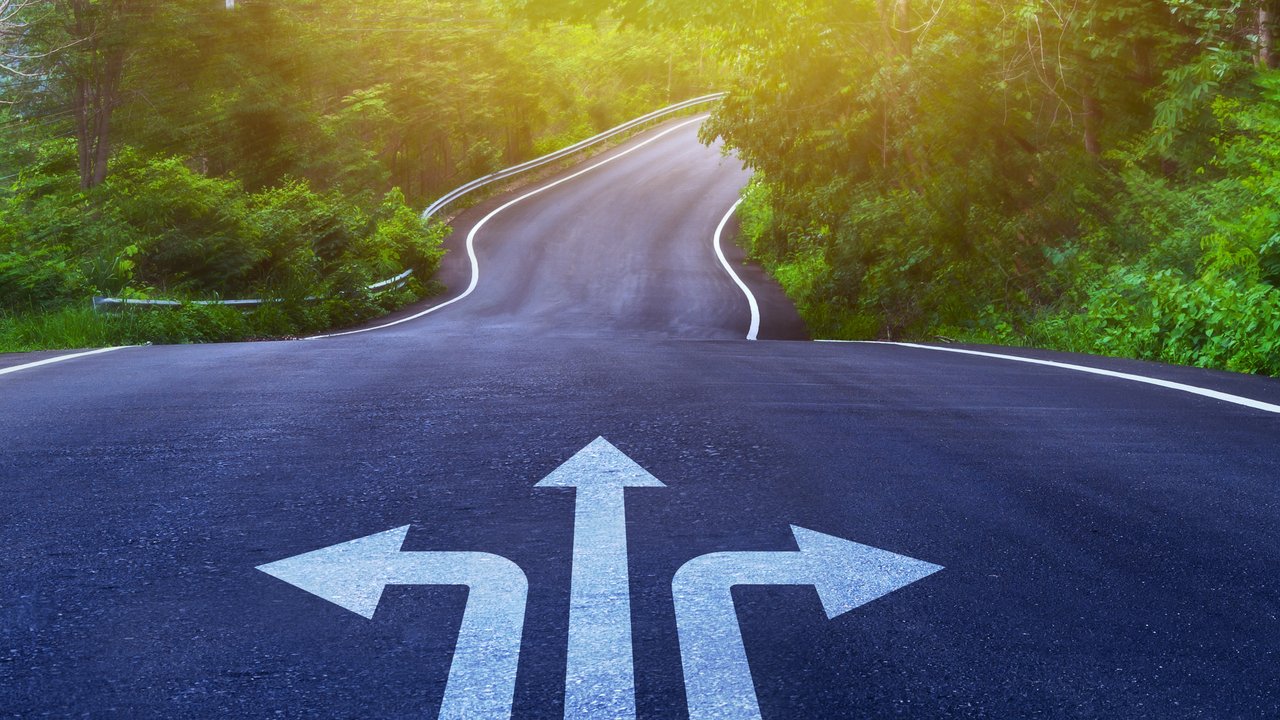 Drei Pfeile auf einer asphaltierten Straße, die in unterschiedliche Richtungen weisen