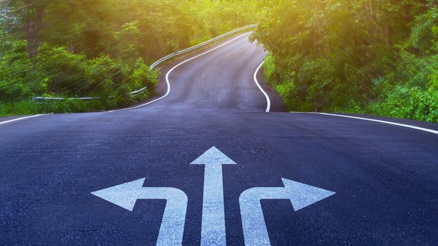 Drei Pfeile auf einer asphaltierten Straße, die in unterschiedliche Richtungen weisen