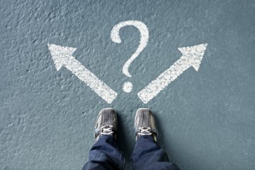 Two feet in sneakers; on the ground two arrows pointing left and right with a question mark in the middle