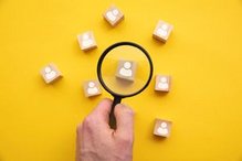 Lupe über Holzwürfeln mit Personensymbol