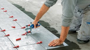 Ein Mann kniet auf dem Boden und befestigt Metallplatten