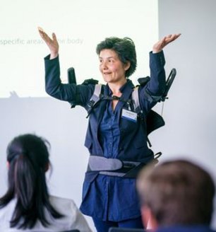 Lîen Wioland vom INRS demonstriert Benutzung von Exoskelett bei Hebetätigkeit