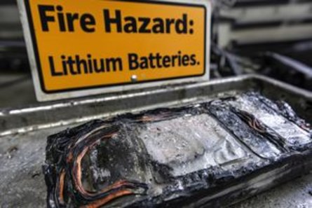 Nahaufnahme einer beschädigten Lithium-Ionen-Batterie mit einem Brandgefahrenhinweis.