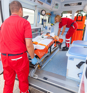 Deux sécouristes embarquent un patient dans une ambulance. 