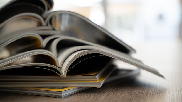 Ein Stapel aufgeschlagener Print-Publikationen