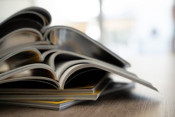 Ein Stapel aufgeschlagener Print-Publikationen